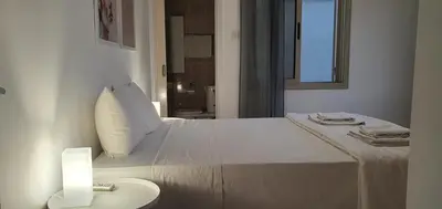 a white bedroom with a bed and a table with a lamp at BLUE LUXURY APARTMENT (BREAKBOOKING CY-SERVICES LTD) in Limassol