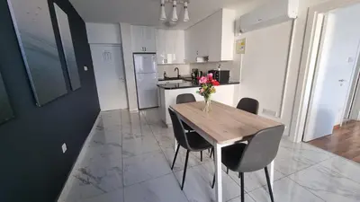 a kitchen with a table with chairs and a vase of flowers on it at Stylish Beach Apt w/ Sea View + Pool + 200Mbit in Larnaka