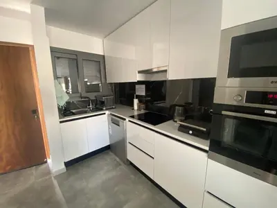 a kitchen with white cabinets and black appliances at Green Bay Area Apartment in Protaras