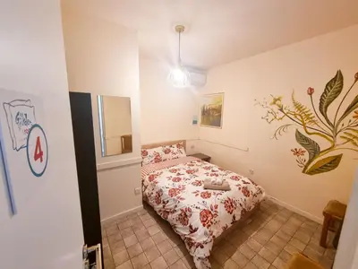 a bedroom with a bed in a room with a painting on the wall at Larnaca Garden Rooms in Larnaka