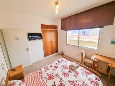 a bedroom with a bed and a table and a window at Larnaca Garden Rooms in Larnaka