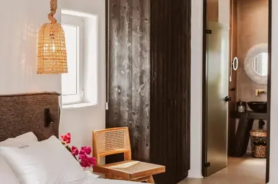 a bedroom with a bed and a chair and a window at Kaliva Suites - Adults Only in Ayia Napa