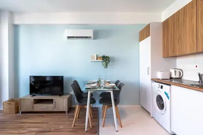 a kitchen with a small table with chairs and a tv at Livia Studio Apartment in Larnaca in Larnaka