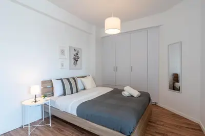 a white bedroom with a bed and a table at Livia Studio Apartment in Larnaca in Larnaka