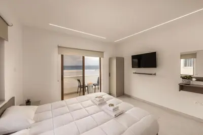 a white bedroom with a large bed and a view of the ocean at SEVIS SUITES in Ayia Napa