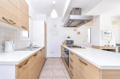 a kitchen with white counter tops and wooden cabinets at Villa Oscar in Protaras