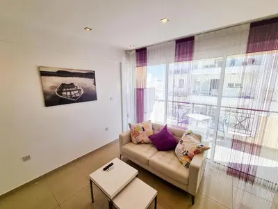 a living room with a couch and a large window at City Vibrance Apartment in Larnaka