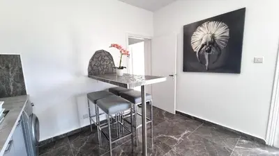 a kitchen with a table and stools in a room at Center 2Br Apt w/ parking and 250m walk from beach in Larnaka