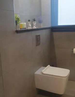a bathroom with a toilet with a window and plants at Deluxe 1 Bed Apt Ayios Dometios in Ayios Dhometios