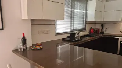 a kitchen with white cabinets and a bottle of wine at STAY Mystique Apartment in Limassol