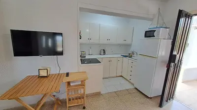 a kitchen with a white refrigerator and a wooden table at Seaside 2BR Apartment 30m from Sea & Free Parking in Voroklini
