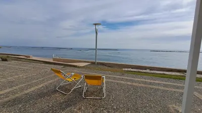 two chairs and a street light next to the water at Seaside 2BR Apartment 30m from Sea & Free Parking in Voroklini