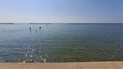 a group of people in the water at the beach at Seaside 2BR Apartment 30m from Sea & Free Parking in Voroklini