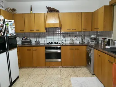 a kitchen with wooden cabinets and a dishwasher at Μοναδικό δωμάτιο in Limassol
