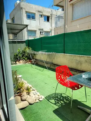 a red chair sitting on a patio with a tennis court at Μοναδικό δωμάτιο in Limassol