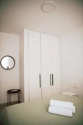 a white bedroom with a bed and a mirror at Sunrise Beach Apartments in Larnaka