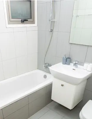 a white bathroom with a sink and a tub and a toilet at Seaview Apartment (Excellent Location) in Larnaka