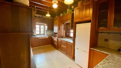a kitchen with wooden cabinets and a white refrigerator at Juliet Suite by TrulyCyprus in Doros