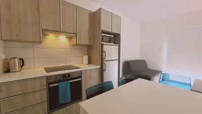 a kitchen with wooden cabinets and a white refrigerator at STAY Beach Wave Apartment in Larnaka