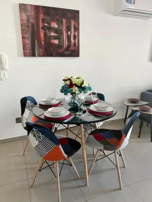 a dining room table with chairs and a table with flowers on it at Oceania bay village Pyla in Larnaka