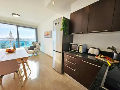 a kitchen with a stainless steel refrigerator and a table at Dios Ponte Finikoudes Beachfront in Larnaka