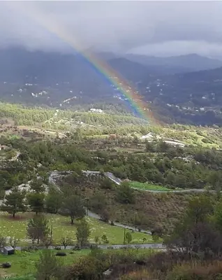 a rainbow over a green field with a road at Koukaki in Kouka