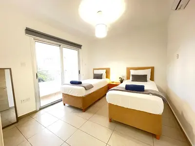 two beds in a room with a window at Aurora Holiday Apartment - Ayia Napa in Ayia Napa