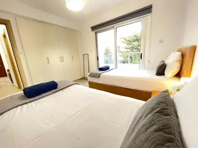 a bedroom with two beds and a window at Aurora Holiday Apartment - Ayia Napa in Ayia Napa