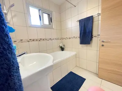 a bathroom with a white tub and a sink and a shower at Aurora Holiday Apartment - Ayia Napa in Ayia Napa
