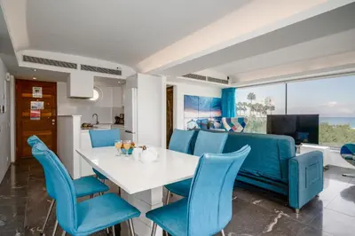a dining room with a white table and blue chairs at Protaras Beachfront Thalassa Suite in Protaras