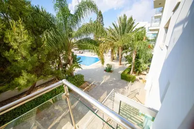 an apartment balcony with a swimming pool and palm trees at Studio in Protaras in Protaras