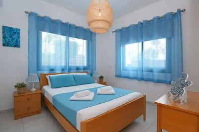 a bedroom with blue curtains and a bed with two towels at Villa Maya - 4bed with Private Heated Pool in Paralimni