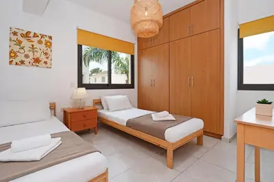 a bedroom with two beds and a desk and windows at Villa Maya - 4bed with Private Heated Pool in Paralimni