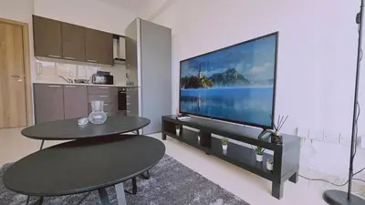 a living room with a tv and two chairs and a table at STAY Cosmo City Suites in Nicosia