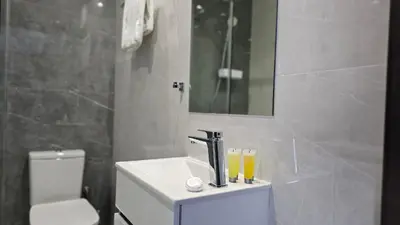 a bathroom with a sink and a toilet and a mirror at STAY Cosmo City Suites in Nicosia