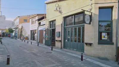an empty street with a building with green doors at STAY Finikoudes Soul in Larnaka