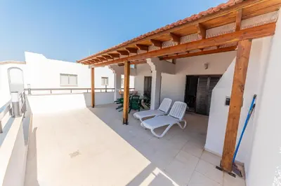 a patio with two white chairs and a wooden pergola at 2 bed, Kapparis, Trinidad - 2A in Paralimni