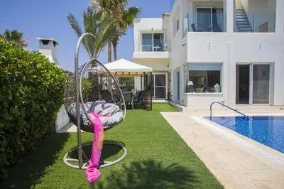 a pink ribbon is tied to a swing by a swimming pool at Villa Elias in Ayia Napa