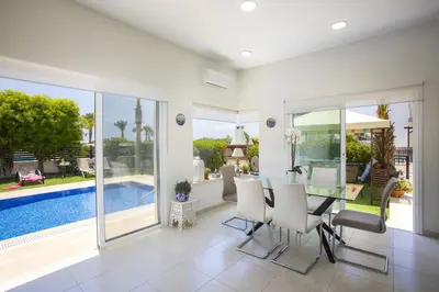 a dining room with a table and a pool at Villa Elias in Ayia Napa