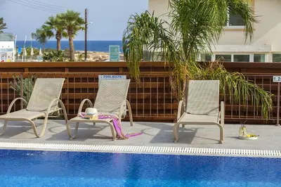 two chairs and a table next to a swimming pool at Theodora in Protaras