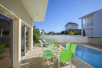 a patio with a table and chairs and a pool at Theodora in Protaras