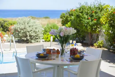a white table with a vase of flowers on it at Protaras Seafront Villa Melissa in Protaras