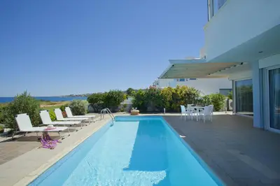 a swimming pool with chairs and a house at Protaras Seafront Villa Melissa in Protaras