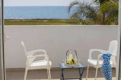 two chairs and a table with a vase on a balcony at Ayia Thekla Sea Front in Ayia Napa