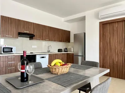 a kitchen with a table with a basket of fruit and a bottle of wine at Kings Boutique Apartment/2BR in Strovolos