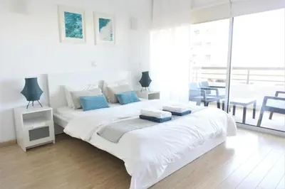 a white bedroom with a large white bed with blue pillows at Eden Dream Apartments in Limassol