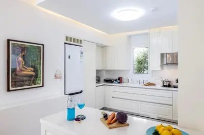 a kitchen with white cabinets and a white refrigerator at Accomoteleia Crystal Lagoon Villa in Protaras