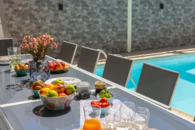 a table with a bowl of fruit next to a pool at Accomoteleia Crystal Lagoon Villa in Protaras
