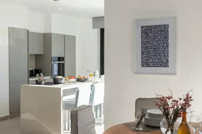 a kitchen with white cabinets and a table in a room at Protaras Periyiali Seaside Villa 33 in Protaras