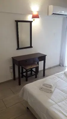 a bedroom with a desk with a mirror and a bed at Boronia Hotel Apartments in Larnaka